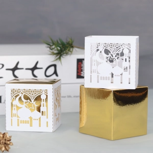 Detailed view of laser-cut moon and star patterns on white and gold Eid candy boxes