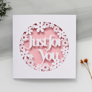 Macro shot of laser-cut 'Just for You' hollow floral greeting card with pink background layer
