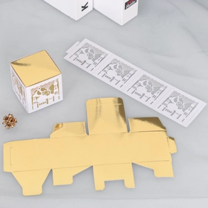 Detail of laser-cut mosque and moon patterns on gold and white Eid candy boxes