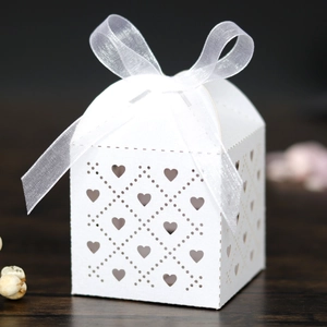 Detail of laser-cut heart pattern on white wedding favor box with a white organza ribbon
