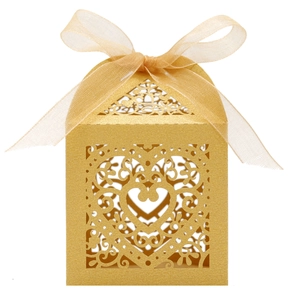 Detail of laser-cut gold glitter wedding candy box with heart pattern and ribbon bow