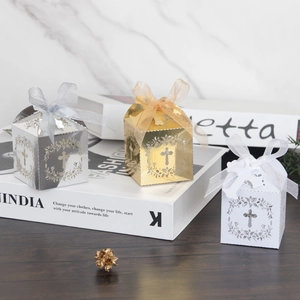 Detailed laser-cut hollow cross favor boxes in gold silver and white with silk ribbons
