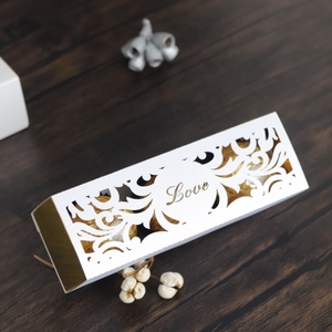 Close-up of white laser-cut Love wedding favor box with gold accents and chocolates