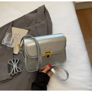 Macro detail of silver patent leather small square bag with golden square clasp