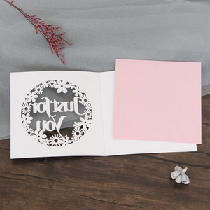Detail of laser-cut Just for You greeting card with pink insert on wooden background
