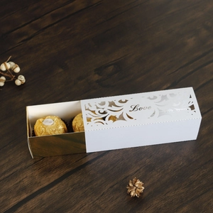 Detail of white hollow Love candy box with golden interior on dark wood table