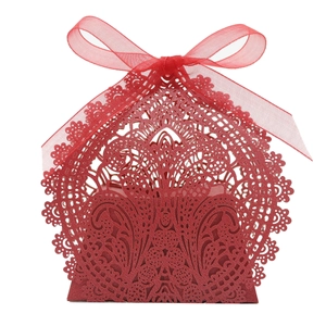 Macro shot of laser-cut floral patterns on red wedding favor box with a silk ribbon bow
