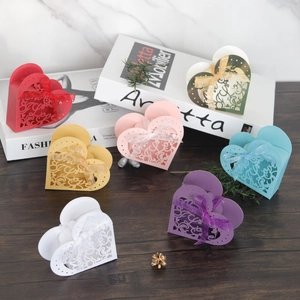 Detail of heart-shaped hollow favor boxes with Love laser cut and silk ribbon bows