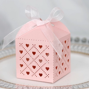 Detail of laser-cut heart pattern on pink wedding favor box with a white ribbon bow