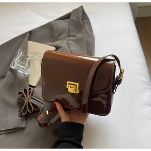 Close-up of brown patent leather crossbody bag with a sleek gold rectangular clasp