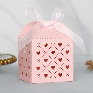 Detail of pink laser-cut gift box with hollow hearts and white ribbon bow decoration