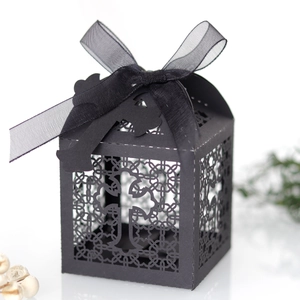 Close-up of black laser-cut favor box with intricate hollow cross and ribbon bow