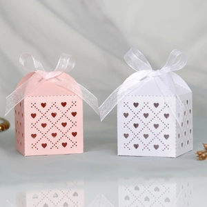 Detailed laser-cut hollow heart pattern on pink and white gift boxes with silk ribbons
