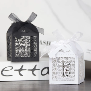 Elegant laser-cut cross favor boxes in black and white with decorative ribbons