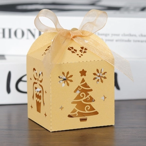 Macro shot of laser-cut Christmas tree patterns and golden ribbon on gift box