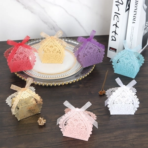 Detail of laser-cut floral wedding favor boxes with elegant ribbon bows in various colors