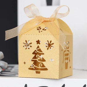 Detail of laser-cut gold Christmas gift box with snowflake patterns and silk ribbon bow
