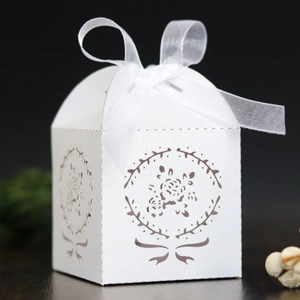 Vue macro boîte à dragées blanche découpée au laser avec motifs floraux et ruban organza