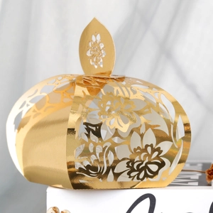 Detail of laser-cut golden pumpkin candy box with floral patterns and leaf handle