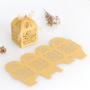 Detailansicht lasergeschnittener Gold-Hochzeitsboxen mit floralem Muster und Seidenband