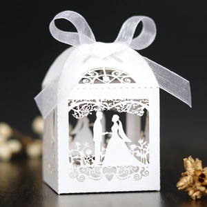 Detailed laser-cut white wedding favor box with ribbon showing bride and groom silhouette