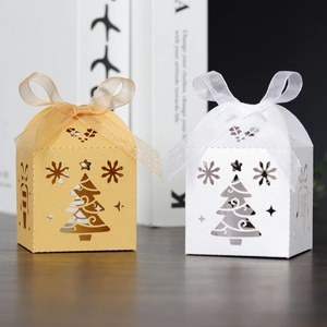 Close-up of laser-cut Christmas tree candy boxes in gold and white with ribbon bows