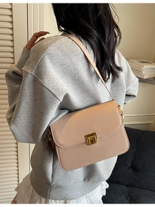 Glossy beige crossbody bag with gold square clasp shown from a side view on a model