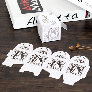 Laser-cut white wedding favor box with ribbon and thank you tag on wood background