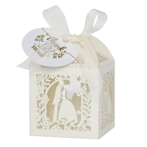Detail of laser-cut ivory wedding favor box with romantic silhouettes and white ribbon