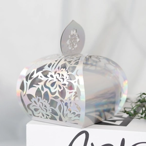 Macro shot of laser-cut silver holographic candy box with floral patterns and leaf handle