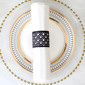 Detail of black hollow geometric napkin ring with diamond cutout on white linen