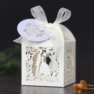 Close-up of laser-cut wedding candy box with bride groom silhouette and silk ribbon