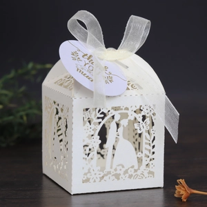 Detail of white laser-cut wedding favor box with bride silhouette and thank you tag
