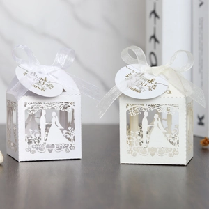 Macro shot of laser-cut wedding favors box with bride and groom silhouette and ribbon