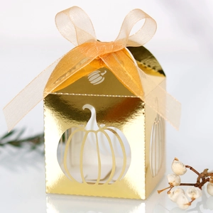 Detailed close-up of golden pumpkin hollow-out paper gift box with orange organza ribbon
