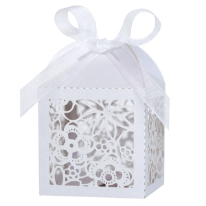 Close-up of laser-cut floral favor box with a white satin ribbon and intricate patterns