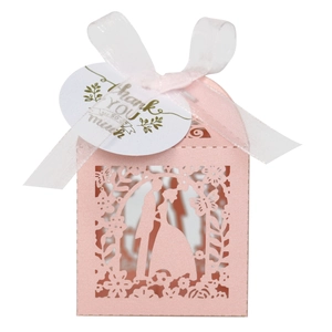 Macro detail of laser-cut pink wedding favor box with ribbon and thank you tag