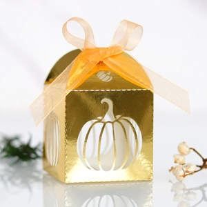 Close-up of golden hollow pumpkin gift box with orange ribbon on reflective surface