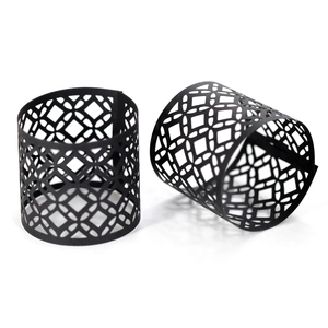 Detail showing two black hollow napkin rings with geometric laser-cut patterns on white background