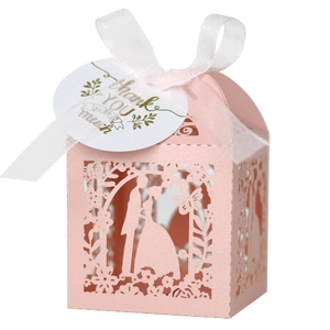 Detail of pink laser-cut wedding favor box with ribbon bow and thank you tag