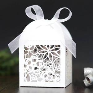 Elegant white laser-cut wedding favor box with floral patterns and a satin ribbon bow