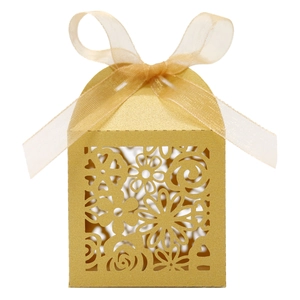 Gros plan d'une boîte à bonbons de mariage dorée découpée au laser avec ruban en organza chic