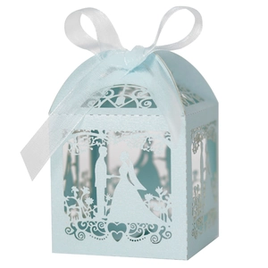 Detail of light blue laser-cut wedding candy box with heart pattern and white ribbon
