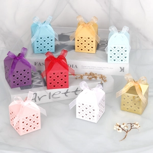 Detail of laser-cut heart favor boxes with satin ribbon bows on marble background
