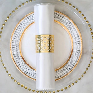 Top view of gold hollow napkin ring with geometric diamond pattern on white linen