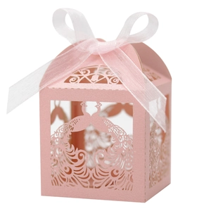 Detail of pink laser-cut wedding favor box with peacock pattern and white ribbon bow