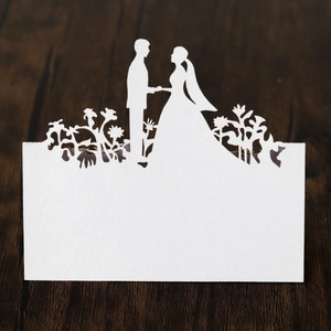Detailed laser-cut bride and groom silhouette wedding place card on wooden background