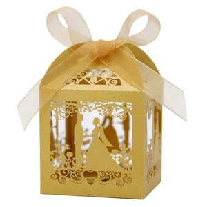 Detail of gold laser-cut wedding favor box with glitter texture and satin ribbon bow