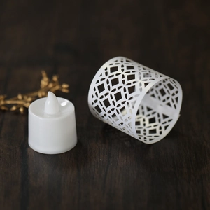 Macro shot of white laser-cut geometric paper sleeve and LED electronic candle