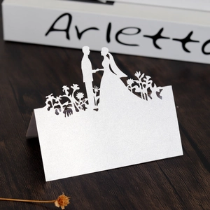 Close-up of laser-cut wedding place card with pearlescent silver finish and floral silhouette